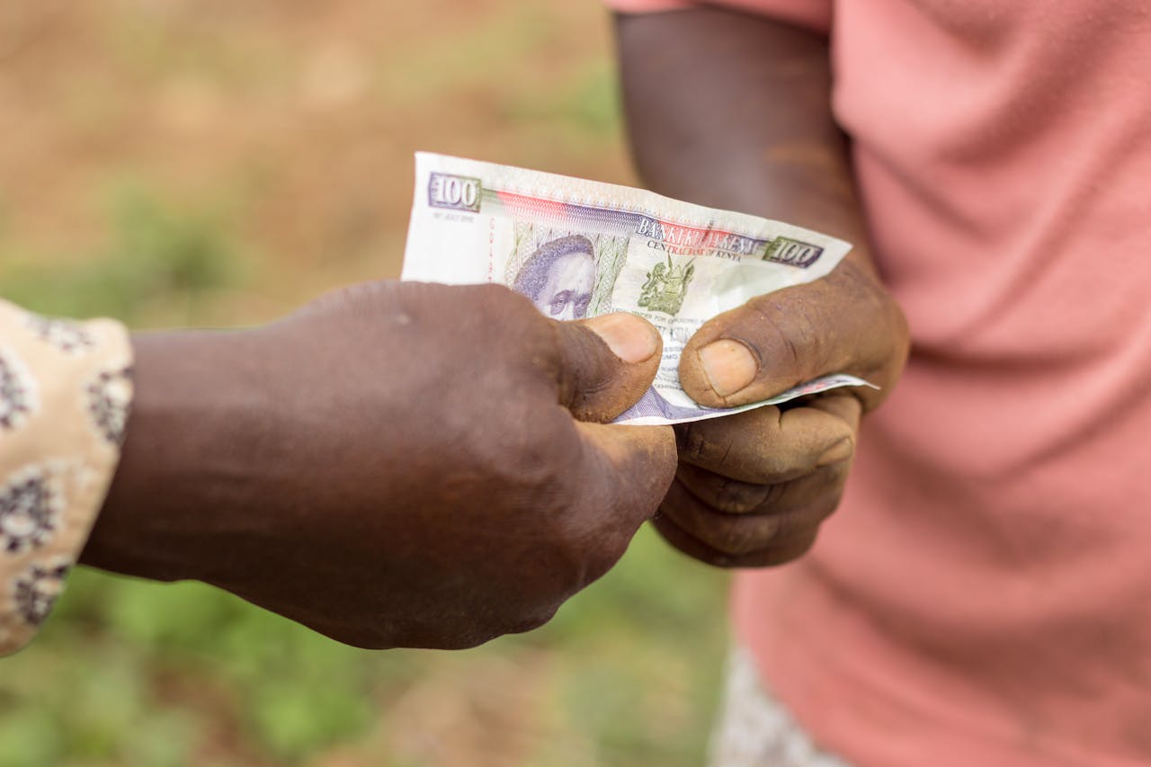 about-01 Captured moment of two individuals exchanging currency outdoors in Kenya.